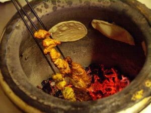 Cooking food in a Tandoori Indian Cooking method in a tandoor grill. Indian cooking method
